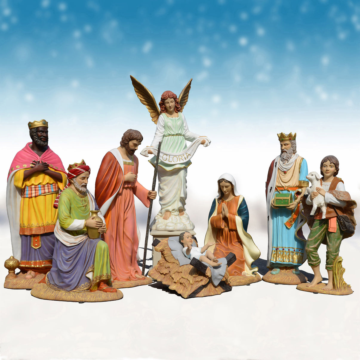 Set of nativity scene figurines with an angel figure in the center against a blue sky background.