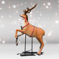Decorative deer figure with antlers and a red harness on a stand against a sparkling background